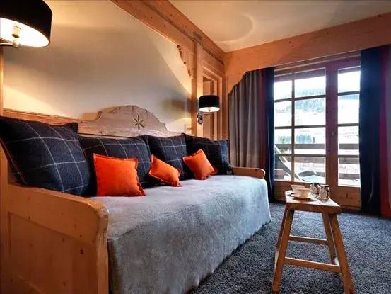 Wohnbereich mit gemütlichem Sofa, grauen Decken und orangefarbenen Kissen im Chalet-Stil