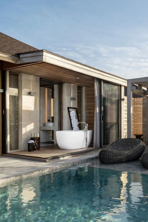 Freistehende Badewanne neben dem Pool mit modernem Außendesign.