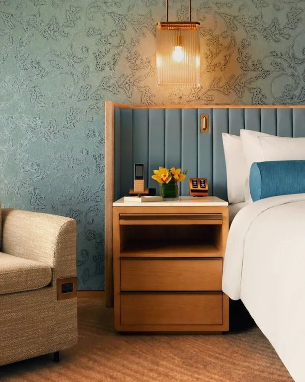 Nachttisch mit moderner Leuchte und Blumen im Marina Bay Zimmer.