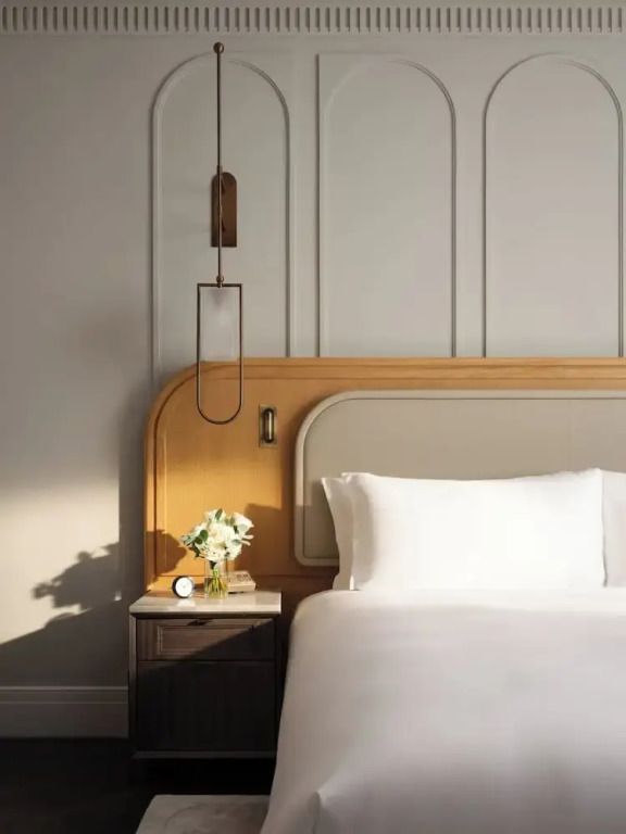 Detailaufnahme eines stilvollen Betthaupts mit moderner Lampe und Blumenarrangement