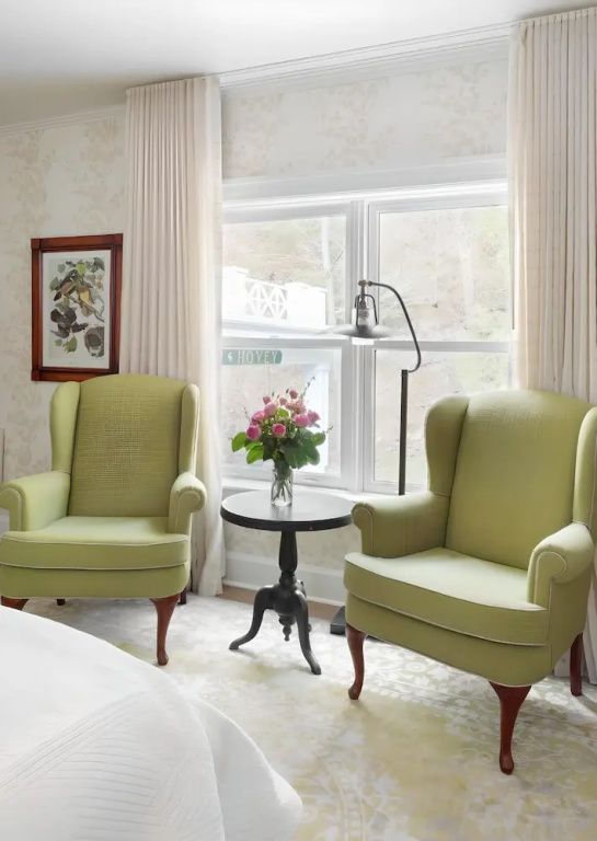 Zwei elegante grüne Sessel mit Beistelltisch und Blumenvase vor einem Fenster