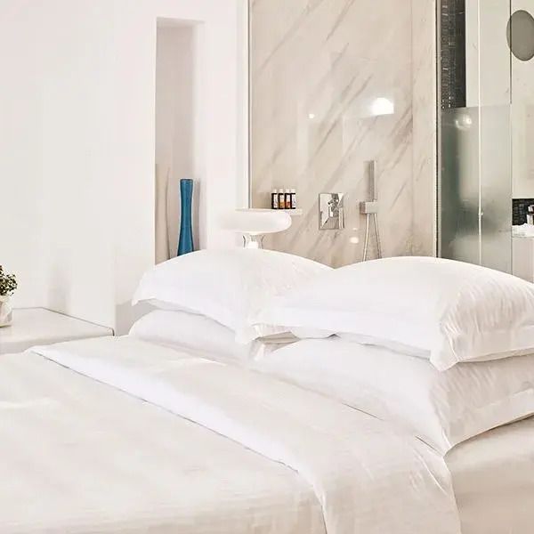 Elegantes Doppelbett in einer modernen Suite mit Glasdusche und minimalistischen Details.