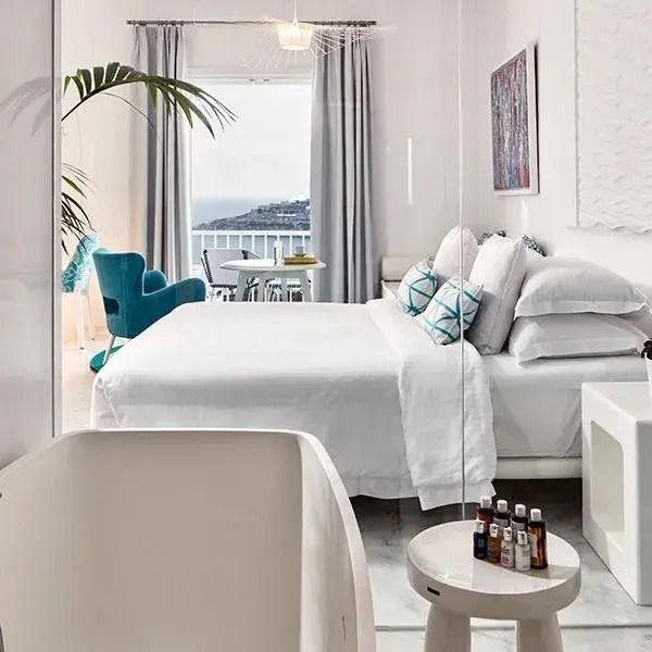Helles Schlafzimmer mit Doppelbett und Terrasse im Myconian Ambassador Hotel