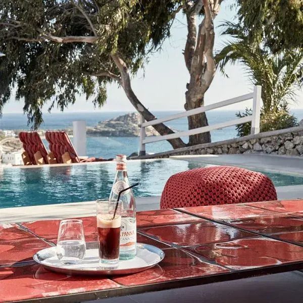Privater Poolbereich mit Meerblick und Tisch mit Getränk.