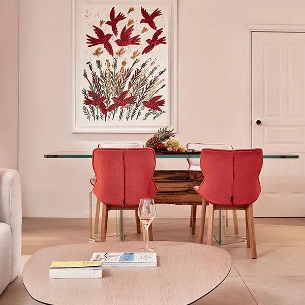 Eleganter Essbereich mit Kunst an der Wand und modernen roten Stühlen.