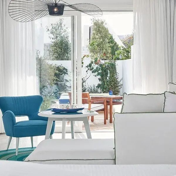 Helles Zimmer mit blauen Akzenten und Zugang zu einem privaten Balkon mit Gartenmöbeln