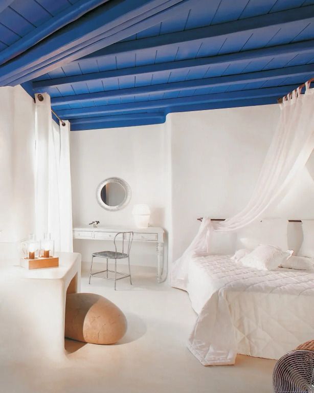 Lichtdurchflutetes Zimmer mit blauer Holzdecke und weißen Akzenten. Gemütliches Bett mit Baldachin.