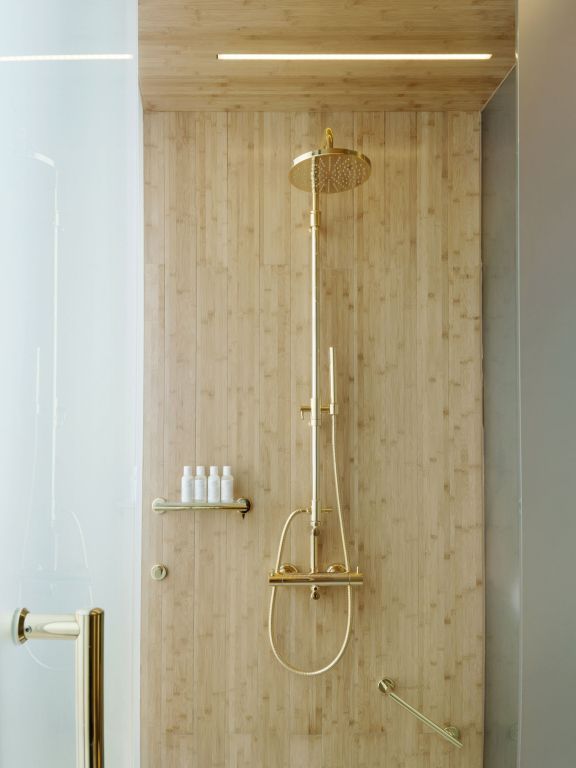 Luxuriöse Dusche mit goldenen Armaturen und natürlicher Holzverkleidung