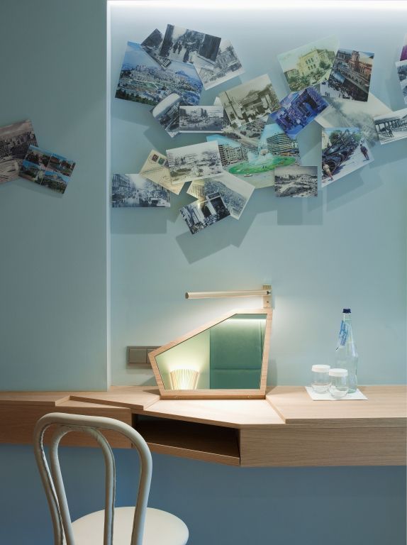 Schreibtisch in Hotelzimmer. Dekorative Fotokollage an der Wand.