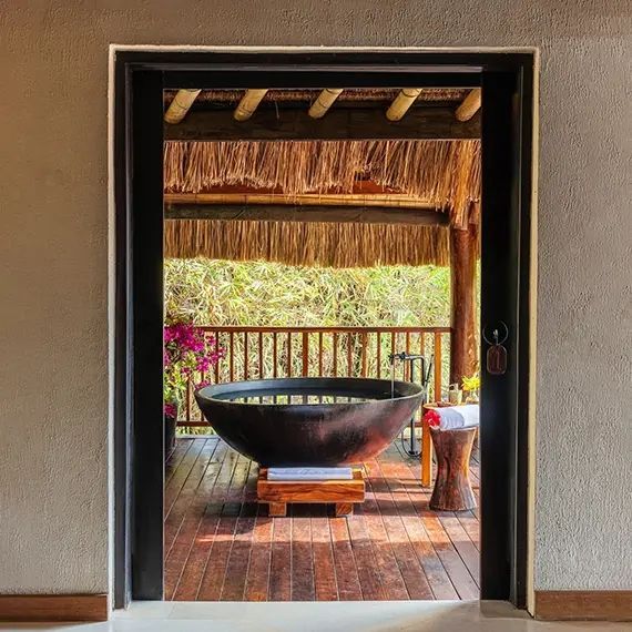 Freistehende Badewanne auf einer Holzterrasse mit Blick auf die Natur
