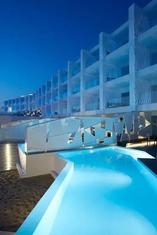 Externe Ansicht bei Nacht mit beleuchtetem Pool und moderner Architektur.