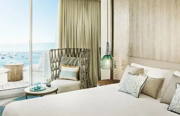 Helles Schlafzimmer mit Blick aufs Meer. Gemütliche Dekoration mit modernem Sessel.