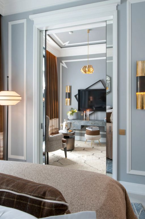 Eleganter Wohnbereich mit großem TV und goldenen Akzenten auf grauem Hintergrund.
