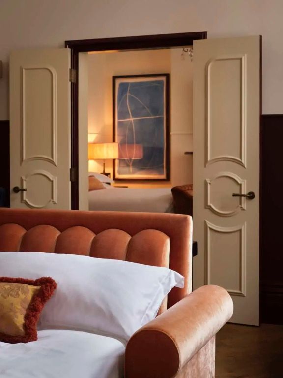 Gemütliches Zimmer mit Blick durch verschnörkelte Türen. Warme Beleuchtung und elegante Einrichtung