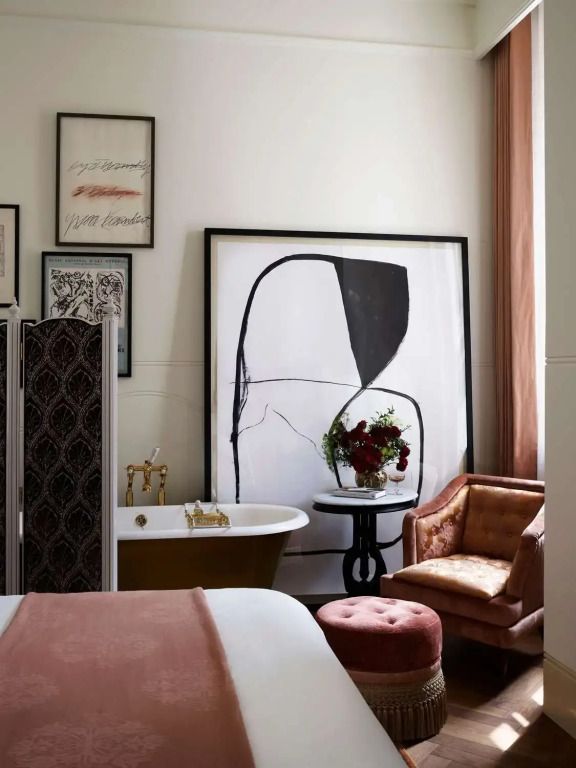 Eckbereich der Suite mit Kunst, eleganter Sitzgruppe und Blick auf eine freistehende Badewanne