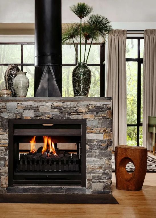 Eleganter Kamin in einer luxuriösen Villa mit Natursteinverkleidung und großen Fenstern.