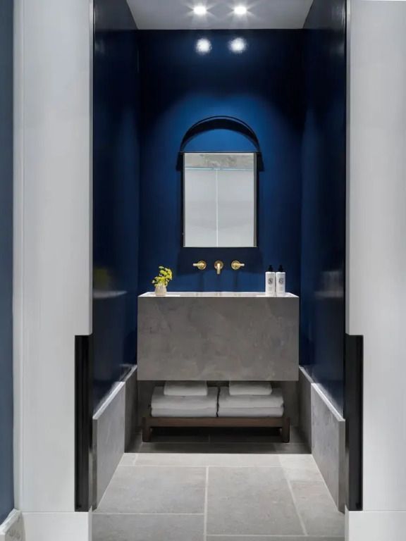 Kleiner Waschbereich mit dunkler blauer Wand und moderner Beleuchtung
