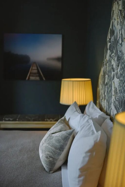 Deluxe Doppelzimmer mit stilvollem Kunstwerk an der Wand und gemütlichem Bett.