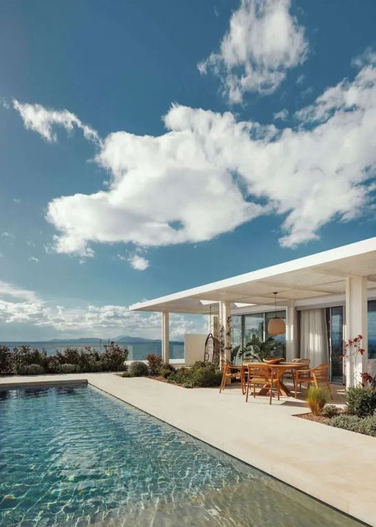 Geräumige Terrasse mit Pool und Meerblick unter blauem Himmel.