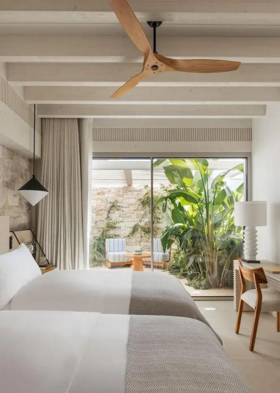 Helles Schlafzimmer mit zwei Betten und direktem Zugang zur begrünten Terrasse