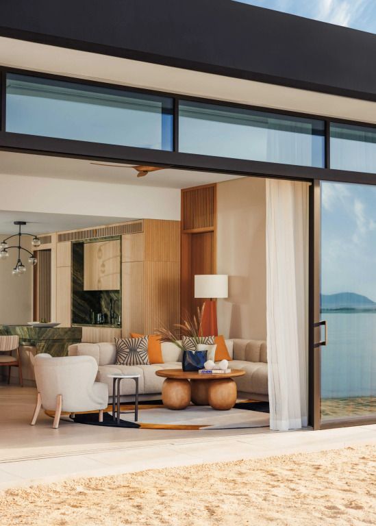 Wohnbereich der Nostos Villa mit Blick auf das Meer durch große Fenster und elegante Einrichtung