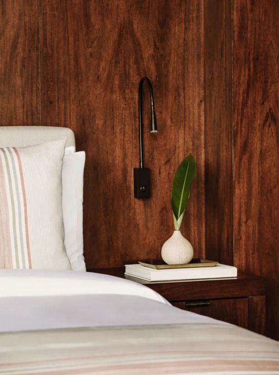 Elegantes Holzdoppelzimmer mit modernem Leseleuchtelement und beruhigender Deko.