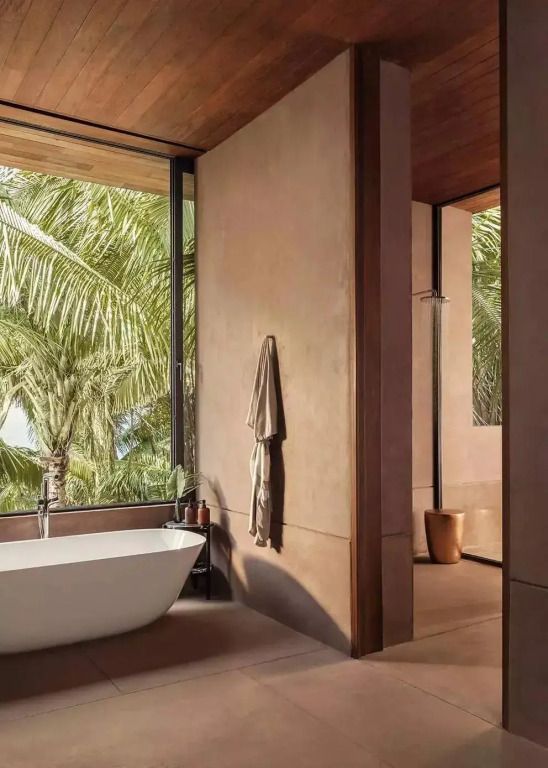 Badezimmer mit freistehender Badewanne und Blick auf Palmen