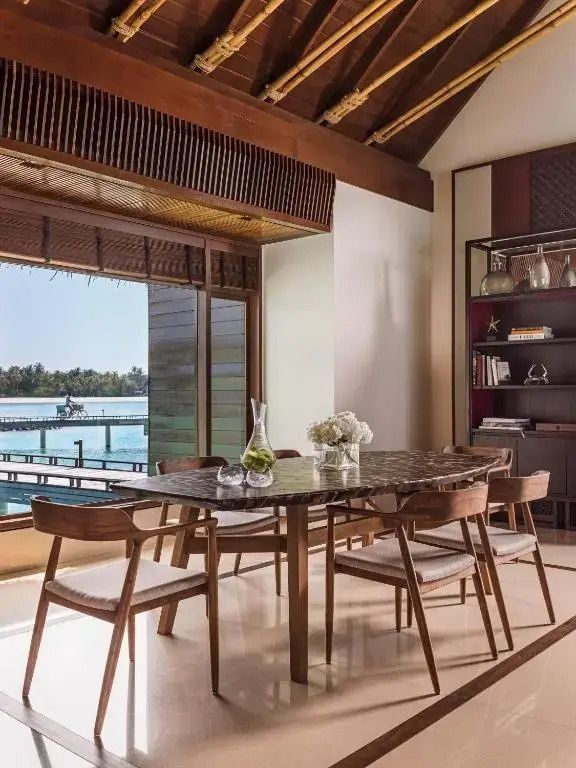Essbereich mit rundem Tisch und Blick auf den Ozean in einer stilvollen Wasser-Villa.