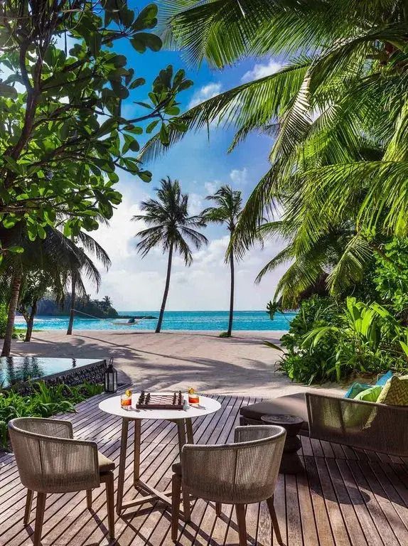 Terrasse mit Blick auf den Strand und Palmen bei sonnigem Wetter