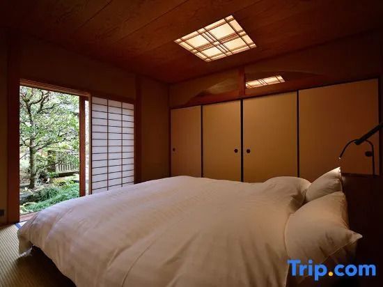 Gemütliches Schlafzimmer mit großem Bett und Blick auf einen Garten durch Shoji-Türen