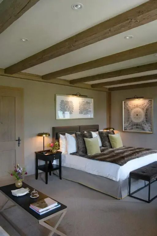 Luxuriös eingerichtetes Schlafzimmer mit Holzbalken und stilvollen Bildern an der Wand.