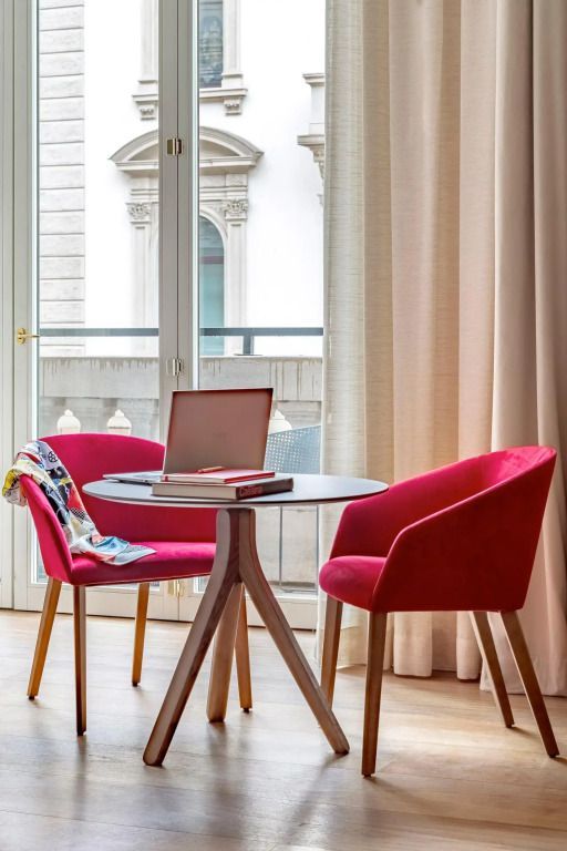 Eleganter Sitzbereich mit zwei roten Stühlen an einem runden Tisch und Balkonblick