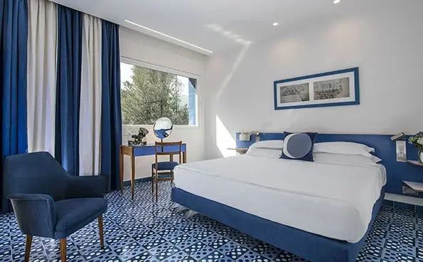 Helles Zimmer mit blau-weißen Fliesen und Doppelbett mit modernen Akzenten.