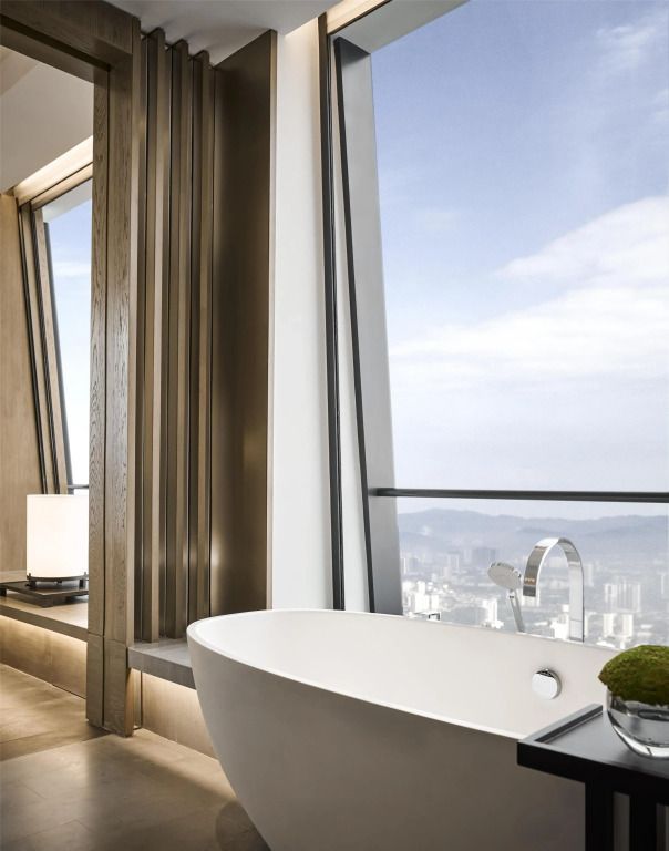 Freistehende Badewanne mit Blick aus dem Fenster auf die Skyline von Kuala Lumpur.