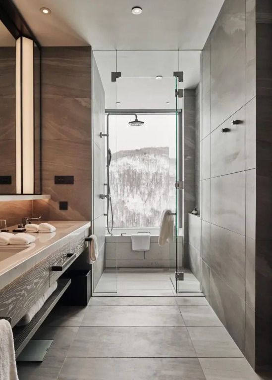 Luxuriöses Badezimmer mit Regendusche und Panoramafenster mit Bergansicht