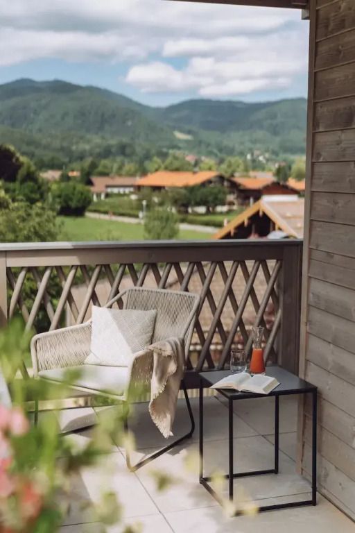 Balkon mit Sitzgelegenheit und Blick auf grüne Landschaft und Berge