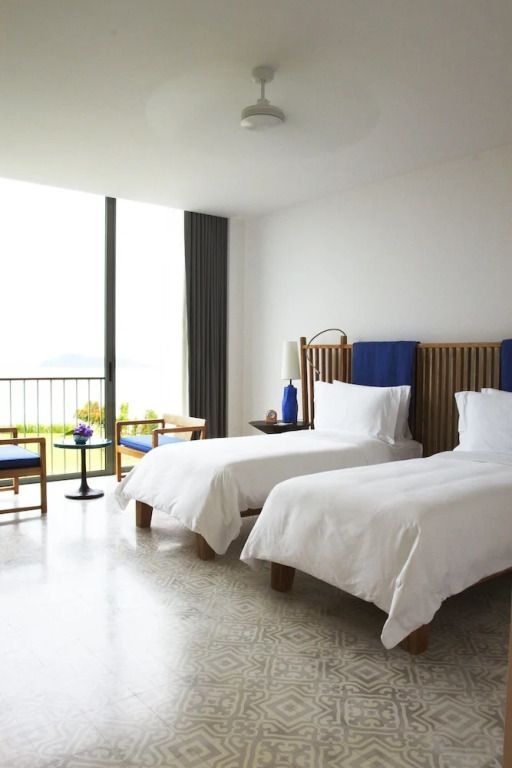 Zwei Einzelbetten in einem hellen Hotelzimmer mit Balkonausblick aufs Meer