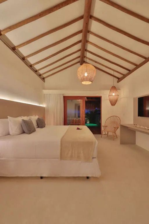 Luxuriöses Schlafzimmer im Bungalow mit Holzbalkendecke und stilvollen Lampen