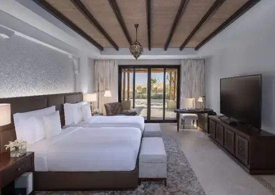 Luxuriöses Schlafzimmer mit zwei Betten und Zugang zur Terrasse im Sahra Villa.