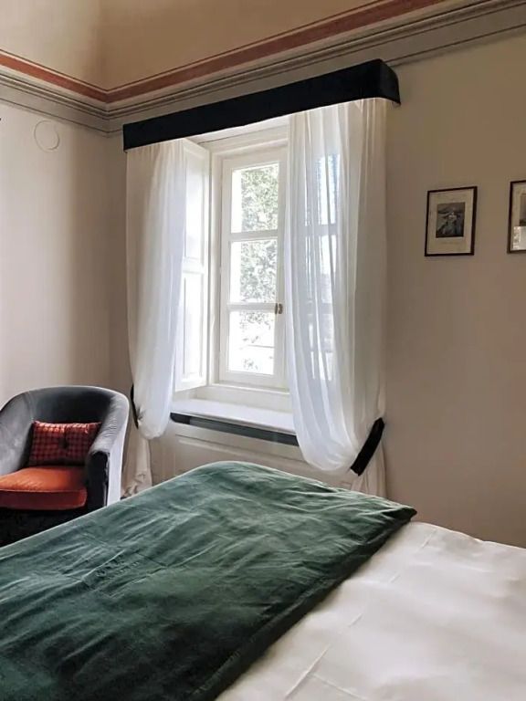 Gemütliches Hotelzimmer mit Blick auf den Garten durch ein großes Fenster.