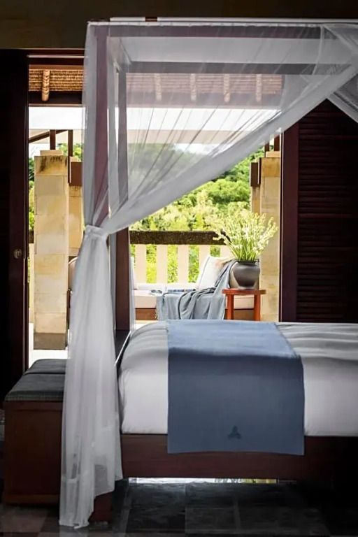 Innenansicht einer Villa mit Himmelbett und Balkon mit grüner Aussicht