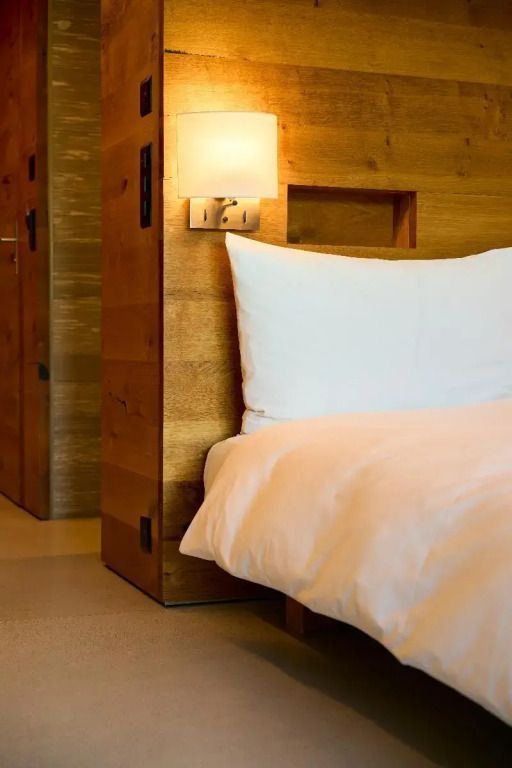 Holzverkleidetes Doppelbett in modernem Hotelzimmer mit sanfter Beleuchtung und angenehmem Ambiente