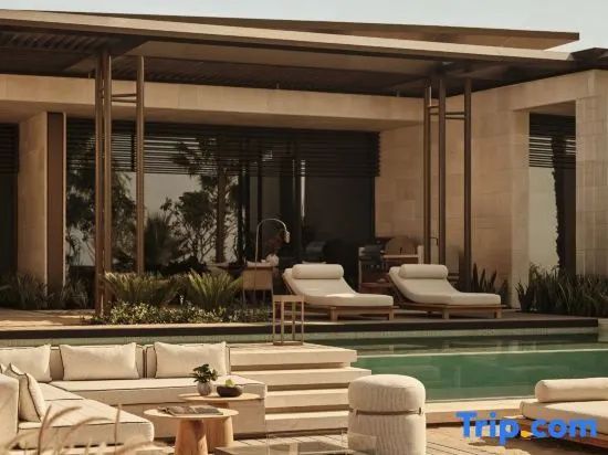 Terrasse mit Lounge-Möbeln und Pool mit Blick auf modernen Gebäudeteil der Villa.