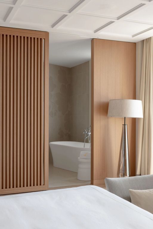 Elegantes Badezimmer mit moderner Badewanne und stilvoller Holzwand im Hintergrund