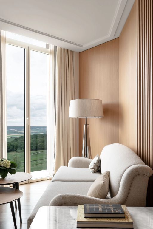 Gemütliche Ecke mit Sofa und Stehleuchte vor einem großen Fenster mit Blick auf die Landschaft