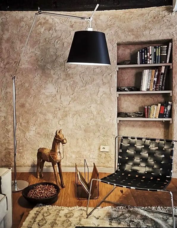Gemütliche Sitzecke mit Sessel, Lampe und Bücherregal an einer rustikalen Wand