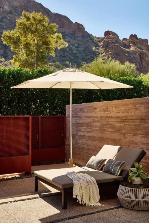 Entspannungsbereich mit Sonnenliege und Sonnenschirm auf privater Terrasse mit Bergblick.