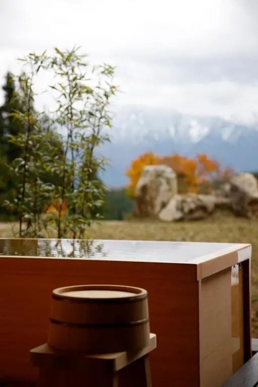 Holzbadewanne und Ausblick auf herbstliche Landschaft im Satoyama Jujo Hotel