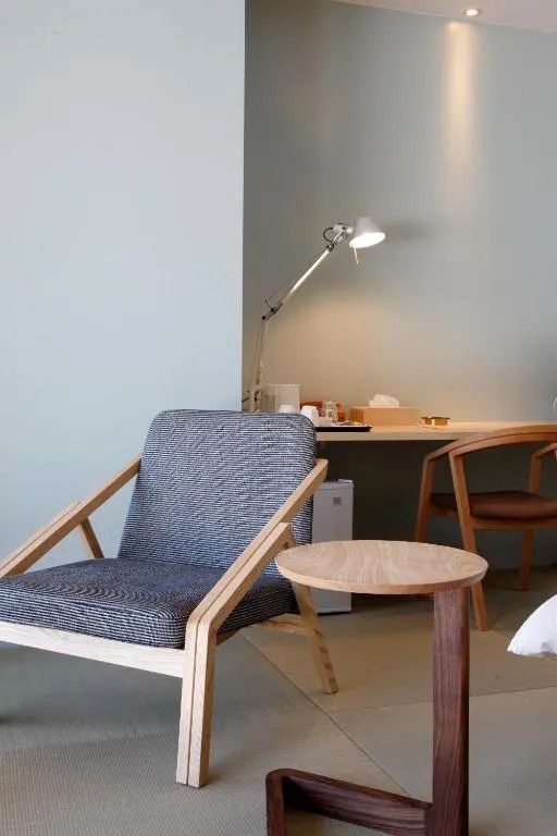 Sitzecke mit Holzstuhl und Schreibtischlampe in modernem Hotelzimmer.