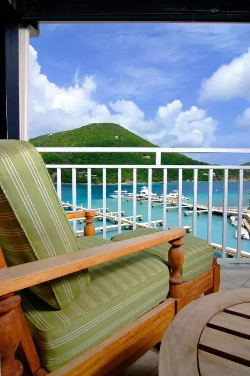 Grüner Sessel auf Balkon mit Blick auf Yachthafen und Hügel